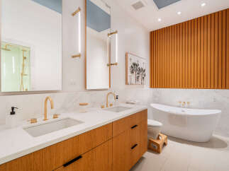 Experience luxury in this modern bathroom featuring a freestanding soaking tub and a dual vanity with sleek gold fixtures.