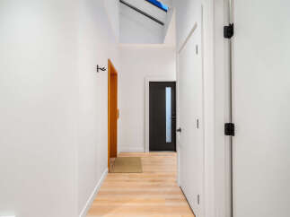 Step into this modern hallway featuring a sleek black door with a frosted glass panel, offering a glimpse of what lies beyond.