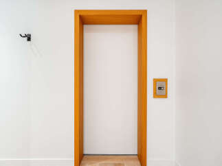 Discover modern living with this sleek, minimalist entryway featuring a clean white door framed by warm oak.