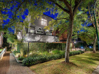 Experience elegant urban living in this stunning property, featuring a modern facade with arched windows and a spacious balcony perfect for enjoying the evening sky.