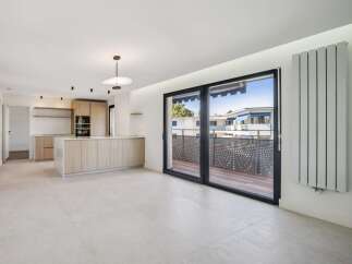Experience modern living in this spacious open-plan apartment featuring a sleek, contemporary kitchen with ample cabinetry and a central island.