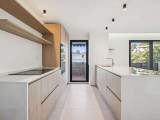 Experience modern living in this sleek, minimalist kitchen featuring light wood cabinetry and pristine white countertops.