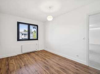 This unfurnished room features a modern aesthetic with clean white walls and a stylish pendant light.