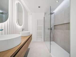 Experience modern luxury in this stunning bathroom featuring dual vessel sinks atop a sleek wooden vanity.