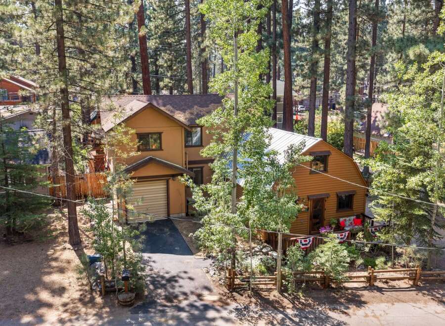 Nestled among tall pine trees, this charming property features a main house with a garage and a separate, cozy cabin.