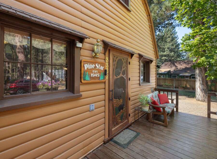 Charming cabin exterior featuring a rustic wooden door with a bear motif and a 'Pine Star Est.