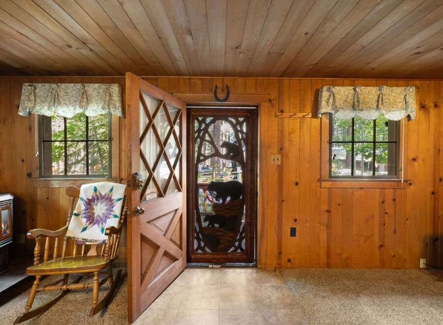 Step into this charming cabin featuring a cozy rocking chair adorned with a quilt, perfect for relaxing by the fireplace.