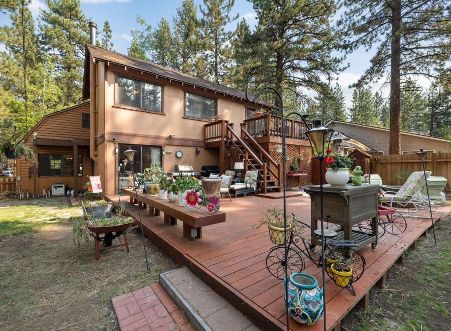 Enjoy outdoor living on this expansive wooden deck, perfect for entertaining or relaxing amidst a lush, wooded setting.