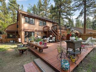 Enjoy outdoor living on this expansive wooden deck, perfect for entertaining or relaxing amidst a lush, wooded setting.