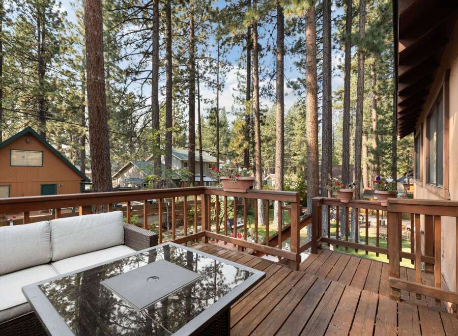 Enjoy the serene mountain lifestyle from this charming deck, perfect for outdoor living amidst tall pine trees.