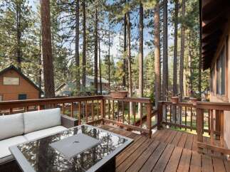 Enjoy the serene mountain lifestyle from this charming deck, perfect for outdoor living amidst tall pine trees.