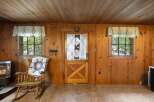 Step into a cozy cabin retreat featuring warm wood paneling throughout and a charming rocking chair adorned with a quilt.