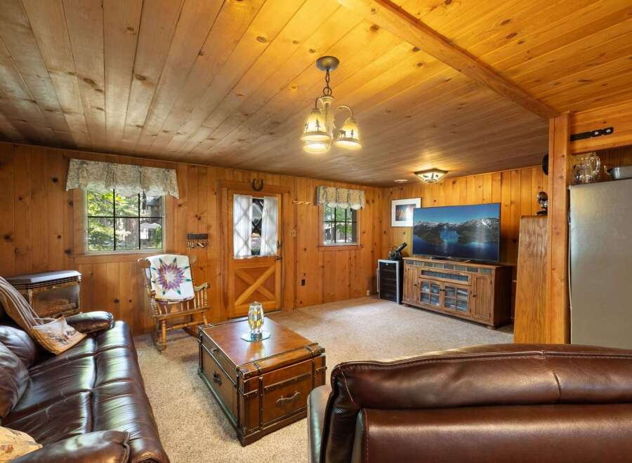 Experience rustic charm in this cozy living room, featuring warm wood paneling throughout and a comfortable leather sofa.