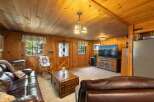 Experience rustic charm in this cozy living room, featuring warm wood paneling throughout and a comfortable leather sofa.