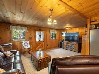 Experience rustic charm in this cozy living room, featuring warm wood paneling throughout and a comfortable leather sofa.