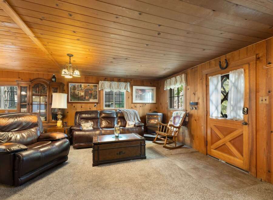 Cozy up in this rustic living room featuring warm wood paneling and a charming fireplace.