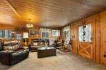 Cozy up in this rustic living room featuring warm wood paneling and a charming fireplace.