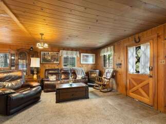 Cozy up in this rustic living room featuring warm wood paneling and a charming fireplace.
