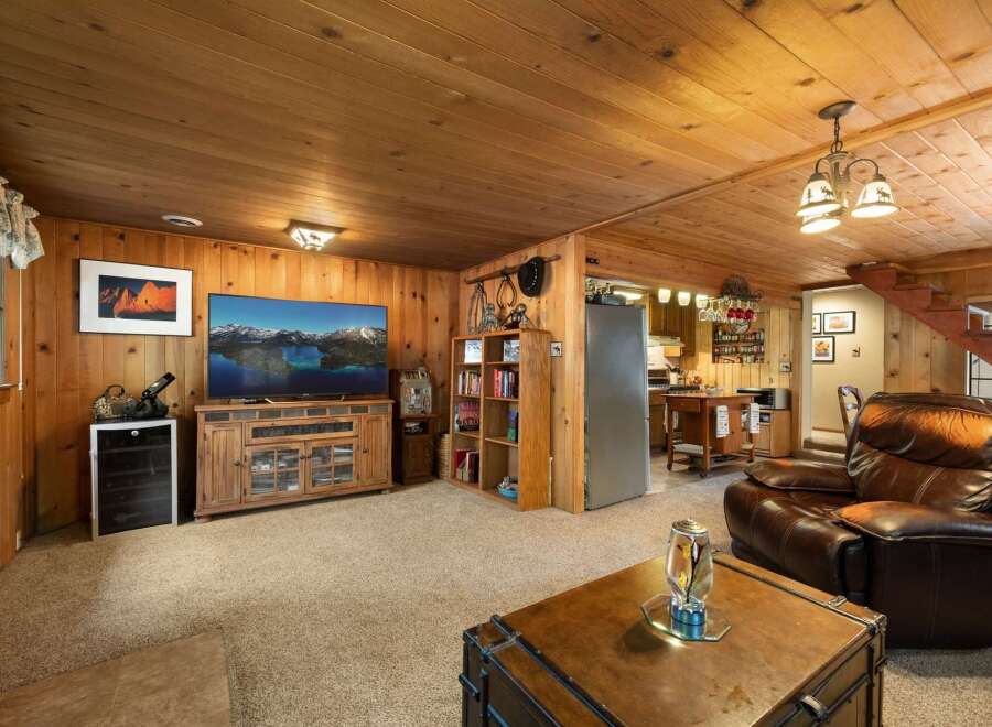 Step into this cozy living space featuring warm wood paneling and a large television perfect for movie nights.