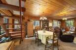 Experience rustic charm in this cozy dining and living area, featuring warm wood paneling and a charming staircase.