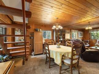 Experience rustic charm in this cozy dining and living area, featuring warm wood paneling and a charming staircase.