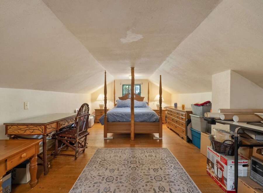 Discover this charming attic bedroom, featuring a cozy four-poster bed and a functional desk area perfect for work or study.