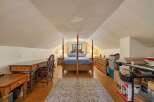 Discover this charming attic bedroom, featuring a cozy four-poster bed and a functional desk area perfect for work or study.