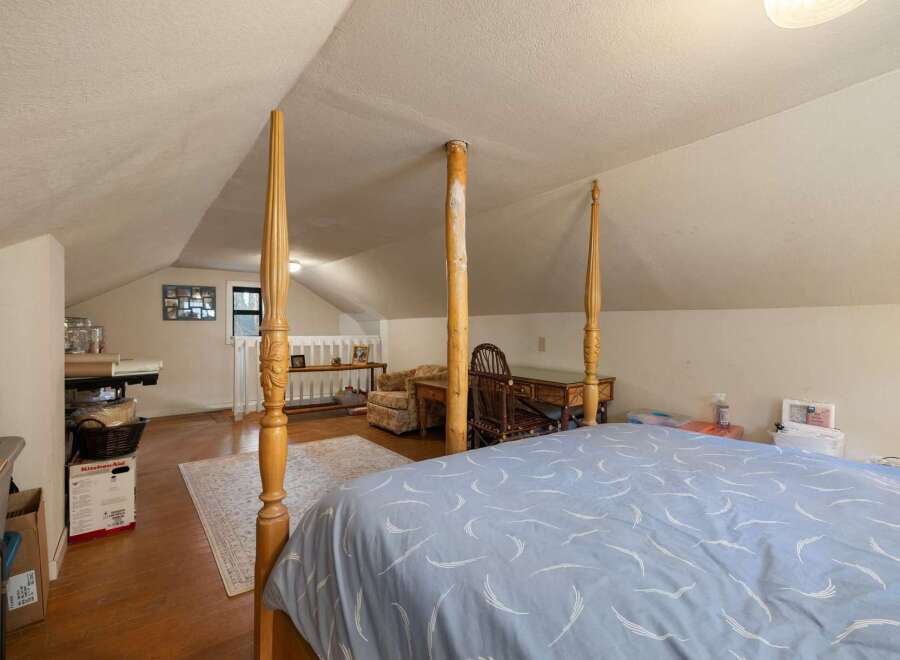 Discover this charming attic bedroom, featuring a cozy four-poster bed and a dedicated workspace with a classic wooden desk and chair.