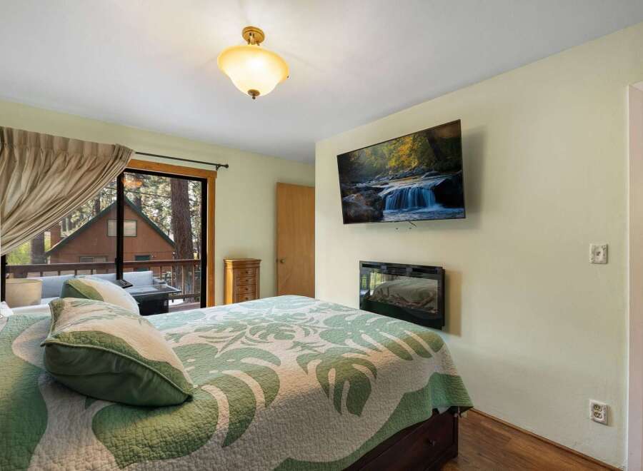 Experience cozy cabin living in this charming bedroom featuring a large bed with a nature-inspired quilt and plush pillows.