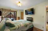 Experience cozy cabin living in this charming bedroom featuring a large bed with a nature-inspired quilt and plush pillows.