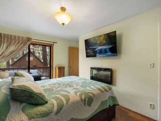 Experience cozy cabin living in this charming bedroom featuring a large bed with a nature-inspired quilt and plush pillows.