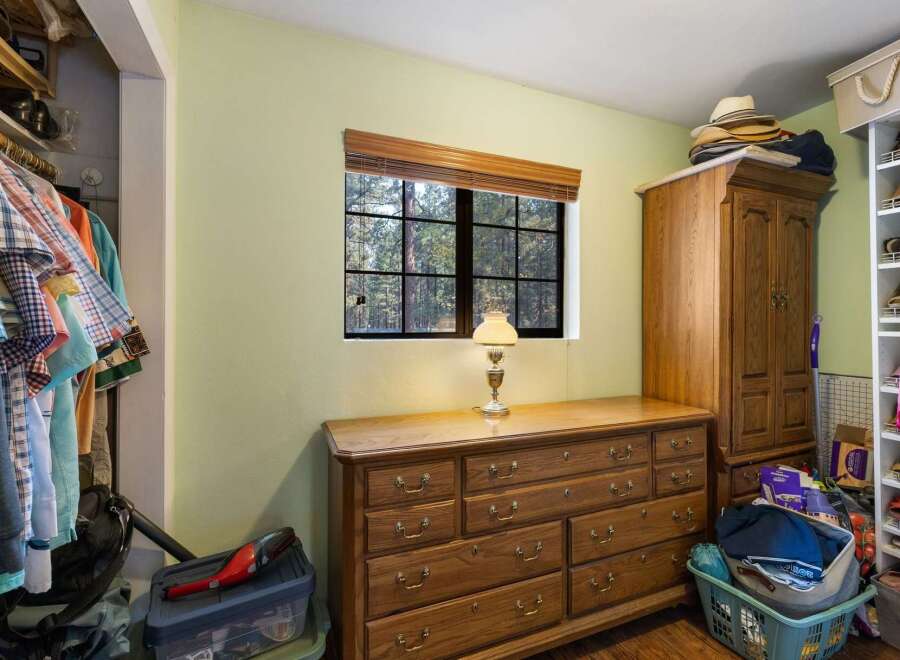 Discover ample storage solutions in this charming bedroom, featuring a spacious wooden dresser and a large wardrobe perfect for organizing your belongings.