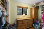 Discover ample storage solutions in this charming bedroom, featuring a spacious wooden dresser and a large wardrobe perfect for organizing your belongings.