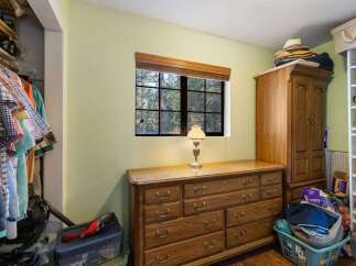 Discover ample storage solutions in this charming bedroom, featuring a spacious wooden dresser and a large wardrobe perfect for organizing your belongings.