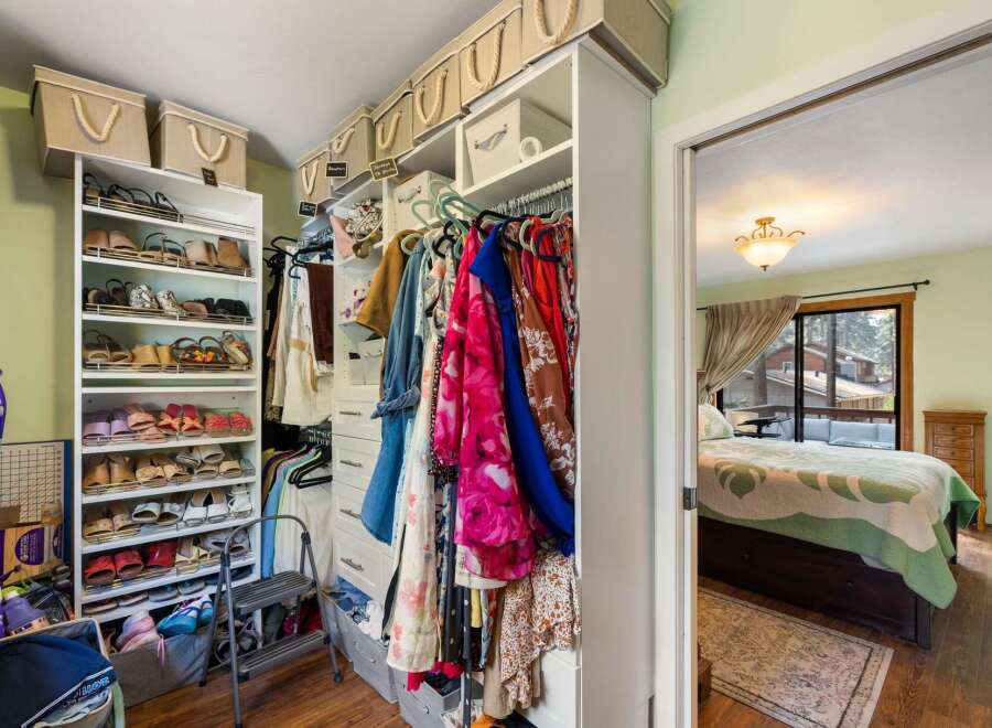 Discover ample storage in this well-organized walk-in closet, featuring multiple shelves for shoes and hanging racks for clothing.