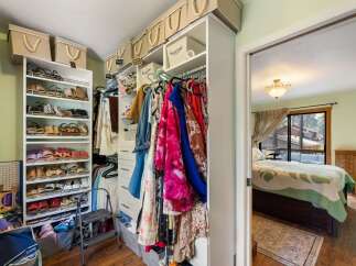 Discover ample storage in this well-organized walk-in closet, featuring multiple shelves for shoes and hanging racks for clothing.