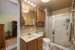 This bathroom features a wooden vanity with a marble countertop and a built-in sink, complemented by a large mirrored medicine cabinet above.
