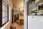 This charming bathroom features a convenient laundry area with a Maytag washer and ample storage shelves stocked with toiletries and towels.