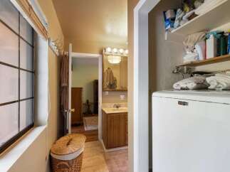 This charming bathroom features a convenient laundry area with a Maytag washer and ample storage shelves stocked with toiletries and towels.