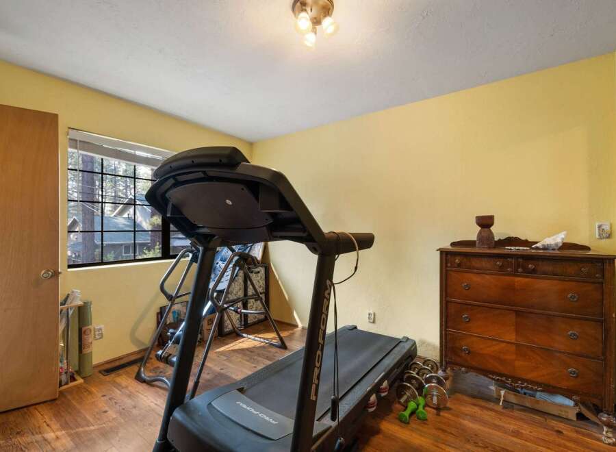 This room is set up as a home gym, featuring a ProForm treadmill and a set of dumbbells.