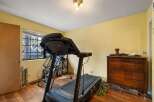 This room is set up as a home gym, featuring a ProForm treadmill and a set of dumbbells.