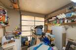 This cluttered garage space offers ample storage potential with shelves lining the walls and a large refrigerator.