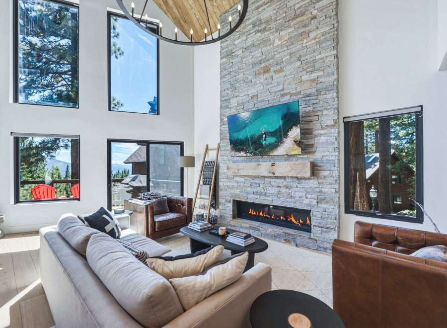 Experience luxury mountain living in this stunning great room, featuring a soaring stone fireplace and expansive windows that frame breathtaking views.