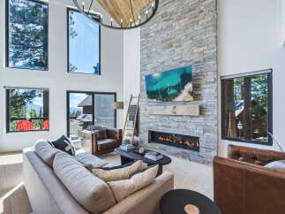 Experience luxury mountain living in this stunning great room, featuring a soaring stone fireplace and expansive windows that frame breathtaking views.