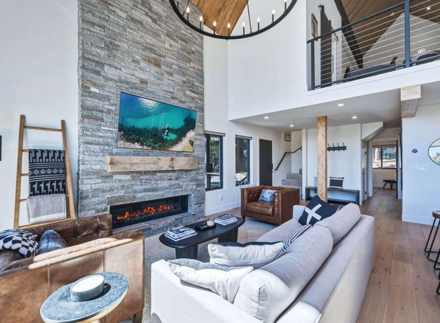 Experience luxury living in this stunning modern mountain home, featuring a soaring stone fireplace as the centerpiece of the open-concept living area.