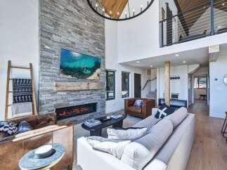 Experience luxury living in this stunning modern mountain home, featuring a soaring stone fireplace as the centerpiece of the open-concept living area.