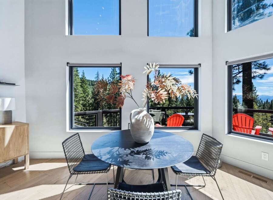 Experience breathtaking panoramic views from this stunning dining area, featuring expansive windows that showcase a lush forest and distant mountains.