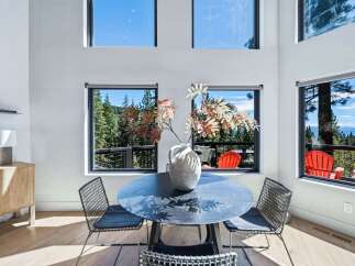 Experience breathtaking panoramic views from this stunning dining area, featuring expansive windows that showcase a lush forest and distant mountains.