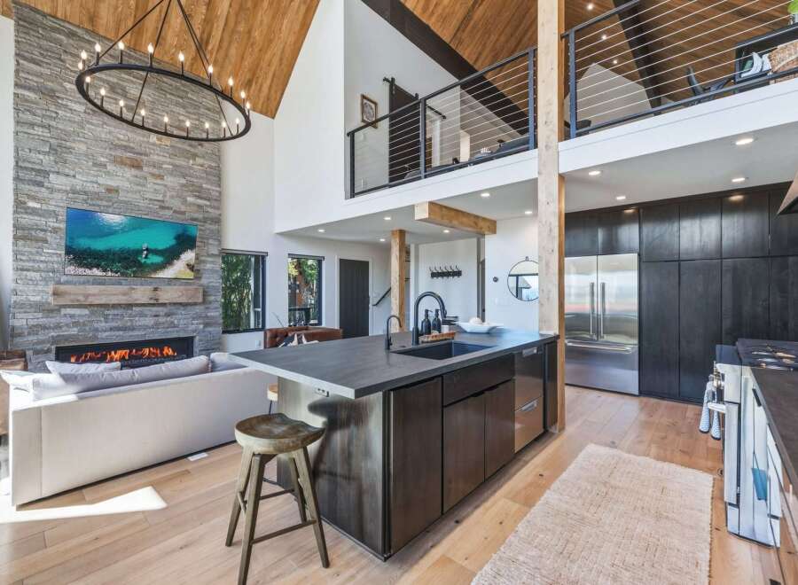 Experience luxury mountain living in this stunning open-concept home featuring a soaring vaulted ceiling with exposed wood beams and a magnificent floor-to-ceiling stone fireplace.