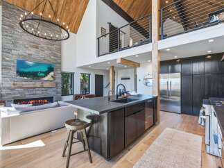 Experience luxury mountain living in this stunning open-concept home featuring a soaring vaulted ceiling with exposed wood beams and a magnificent floor-to-ceiling stone fireplace.